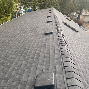 Close up of a chimney on a residential roof with brand new gray shingles installed by High Definition Roofing